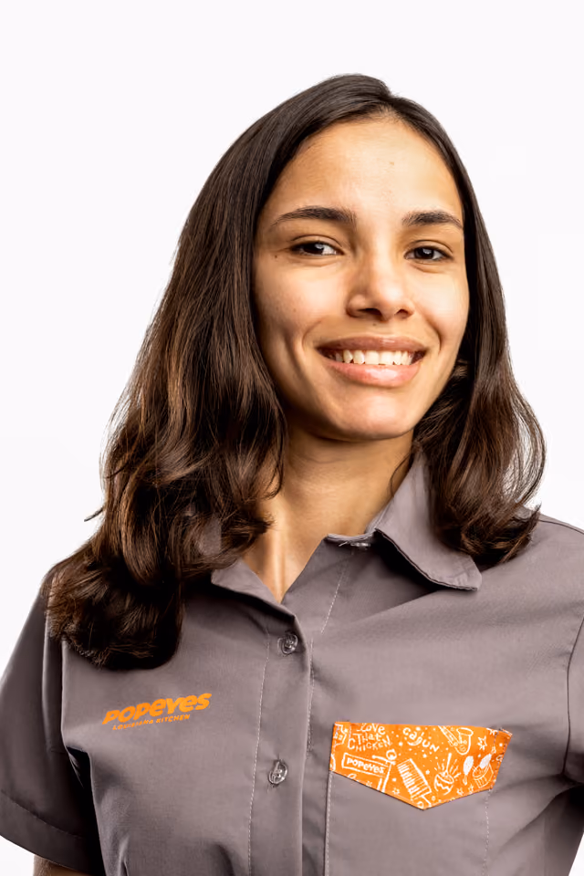 Profissional do Popeyes sorrindo; em seguida, a foto troca e ele(a) aparece mordendo um pedaço de frango