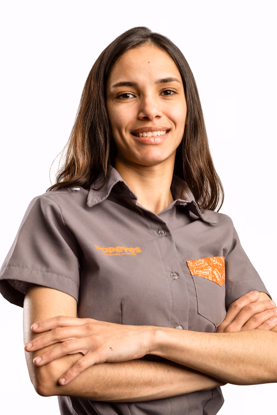 Profissional do Popeyes de braços cruzados; em seguida, a foto troca e ele(a) aparece mordendo um pedaço de frango